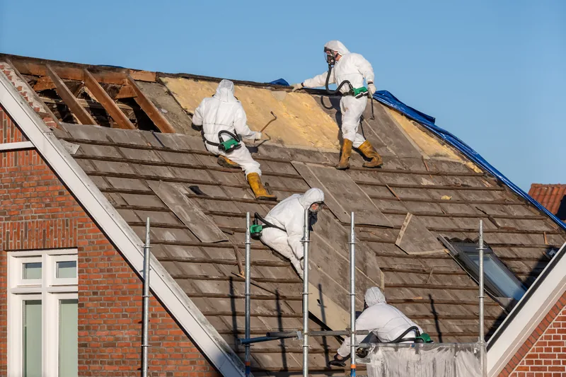 EUROSAN team verwijdert asbestleien van een hellend dak met ademhalingsbescherming